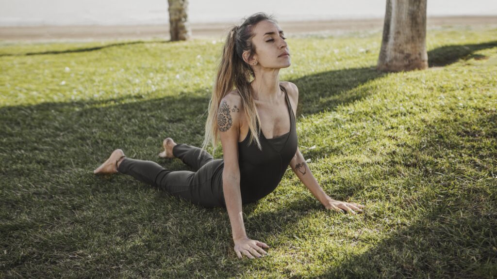 Mulher praticando meditação em ambiente natural, cercada por plantas verdes, representando bem-estar integral e hábitos sustentáveis